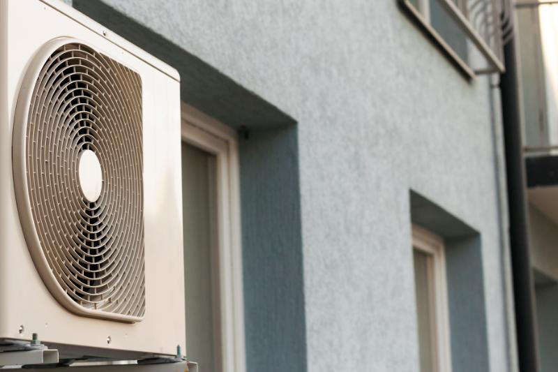 un climatiseur blanc posé sur le côté d'un bâtiment