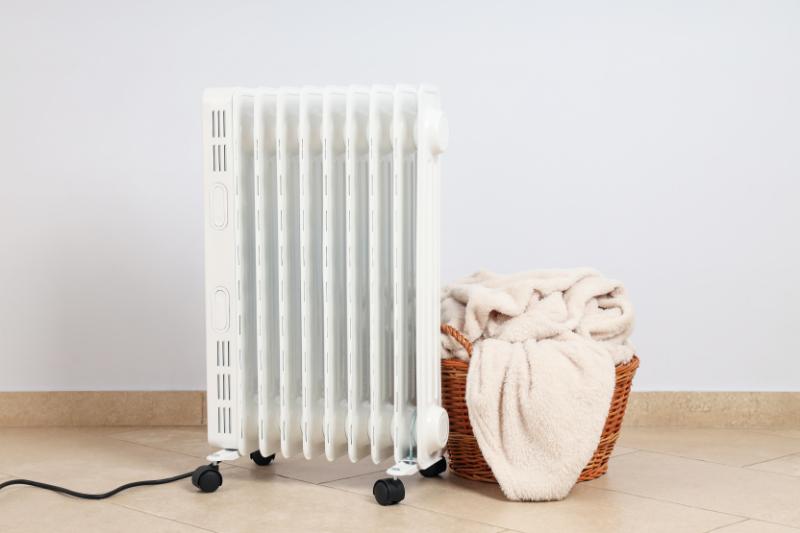 un radiateur blanc à côté d'un panier de serviettes