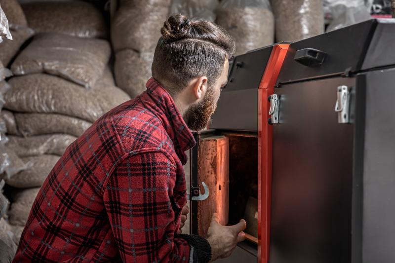 un homme vêtu d'une chemise à carreaux rouges et noirs regardant dans un four